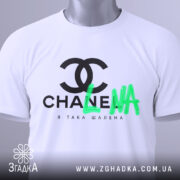 Футболка я така шалена, біла, складена на плоскій поверхні, з верхнього ракурсу, фон світло-сірий, принт чорний з логотипом та зеленим написом 'LNA', з етикеткою на комірці.