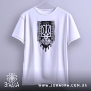 Футболка я українець принт білого кольору, підвішена на вішалці, фон світло-сірий, принт чорного кольору з тризубом та українським орнаментом, видно короткі рукави.