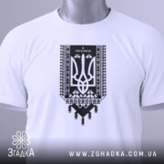 Футболка я українець принт білого кольору, складена на столі, фон світло-сірий, принт чорного кольору з тризубом та українським орнаментом, на комірці видно етикетку.