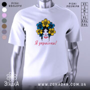 Футболка я українка, білого кольору, зображена на манекені, фон світло-сірий, принт з дівчиною з квітами в волоссі, текст "Я українка!" червоним кольором.