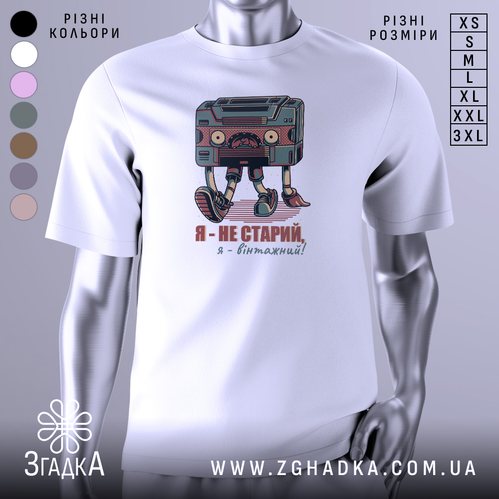 Футболка я вінтажний, білого кольору, зображена на манекені, фон світло-сірий, принт з касетою та написом "Я - не старий, я - вінтажний!" у кольорах червоного та зеленого.