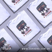 Футболка я вінтажний, білого кольору, зображена на манекені, фон світло-сірий, принт з касетою та написом "Я - не старий, я - вінтажний!" у кольорах червоного та зеленого.