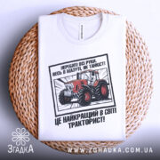 Футболка як танкіст тракторист, біла, зображена зверху на плетеній основі, фон нейтральний, принт з червоним трактором та текстом на українській мові.