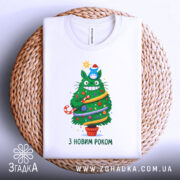Футболка ялинка новий рік, біла, зображена на плетеному кошику, фон світлий, принт з веселим зеленим деревом, яке має червону шапочку, прикрашене іграшками та написом 'З НОВИМ РОКОМ'.