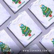 Футболка ялинка новий рік, біла, зображена на манекені, фон сірий, принт з веселим зеленим деревом, яке має червону шапочку, прикрашене іграшками та написом 'З НОВИМ РОКОМ'.