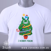 Футболка ялинка новий рік, біла, зображена на столі, фон світлий, принт з зеленим деревом, яке має червону шапочку, прикрашене іграшками та написом 'З НОВИМ РОКОМ', на футболці є бірка.