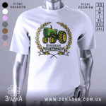 Футболка ідеальний тракторист, біла, зображена на манекені з правого боку, фон світло-сірий, принт з трактором зеленого кольору, оточений жовтими листям і написом 'Ідеальний тракторист'.