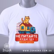 Футболка їду дахом, біла, зображена з верхнього ракурсу, фон світлий, принт з котом на даху будинку, що їде на вантажівці, текст червоним кольором, на комірці видна етикетка.