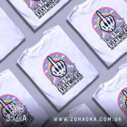 Футболка єдинороги іронія, біла футболка з коротким рукавом, зображена на манекені з ближнього ракурсу, фон світло-сірий, принт з чорним малюнком руки з середнім пальцем, оточений кольоровими елементами, включаючи райдугу та єдинорогів.