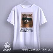 Футболка єнот гумор, біла, підвішена на вішалці, фон світлий, принт з єнотом у темних окулярах та текстом 'Why are you looking at me?'.