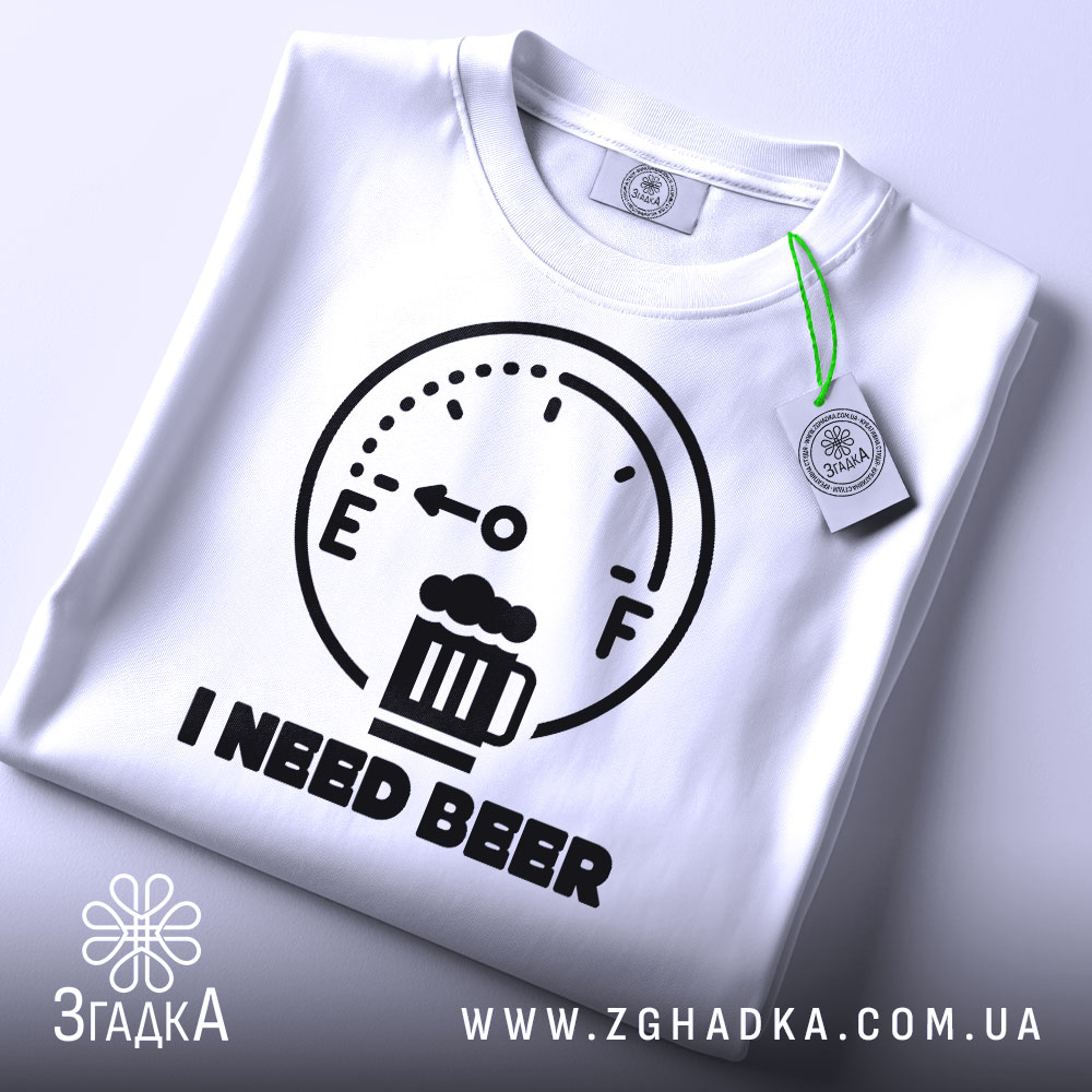 Футболка індикатор пива, біла, складена на столі, фон світло-сірий, принт з індикатором рівня пива та написом 'I NEED BEER' чорного кольору, з етикеткою на рукаві.