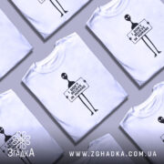 Футболка інопланетянин, біла, зображена з правого ракурсу на манекені, фон світло-сірий, принт чорного кольору з інопланетянином, що тримає табличку з написом 'I DON'T BELIEVE IN HUMANS'.