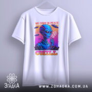 Футболка інопланетний чіл, біла, підвішена на вішалці, фон світло-сірий, принт з інопланетянином, який курить, кольори принта яскраві: синій, рожевий, оранжевий, текст 'WE COME IN PEACE' і 'CHILL'.