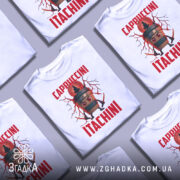 Футболка Itachini Cappuccini білого кольору, зображена з близького ракурсу на манекені, фон нейтральний, принт зображає кавовий стакан з великими червоними очима та блискавками, текст 'Cappuccini Itachini' виконаний червоним кольором.