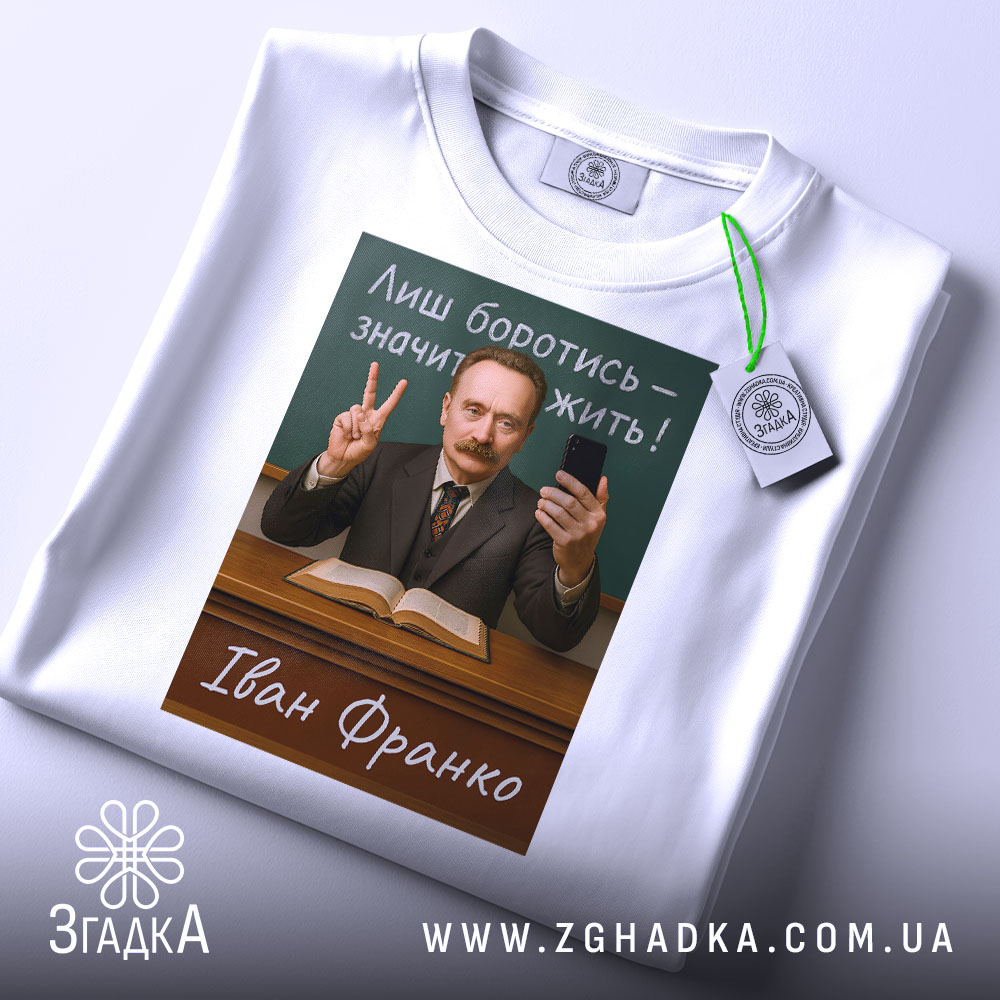 Футболка Іван Франко, біла, складена на поверхні, фон світлий, принт з портретом Івана Франка, текст "Лиш боротись – значить жить!" на зеленому фоні, чоловік у костюмі з бородою, тримає телефон і показує знак миру, на футболці є етикетка.
