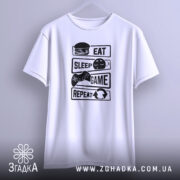 Футболка їж спи білого кольору, зображена з фронтального ракурсу на вішалці, фон світлий, принт чорного кольору з написами 'EAT', 'SLEEP', 'GAME', 'REPEAT' та ілюстраціями гамбургера, ігрового контролера і смайлика.