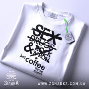 Футболка just coffee білого кольору, зображена зверху, на фоні світло-сірого кольору, принт чорного кольору з текстом 'SEX DRUGS & ROCK 'N' ROLL' та 'just coffee for me, thanks', з зеленим ярликом.