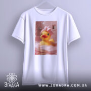 Футболка качка релакс, біла, зображення качки в рожевій ванні з піною, качка в рушнику на голові, підвішена на вішалці, фон з рожевими плитками.