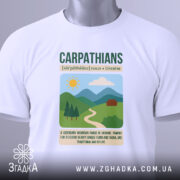 Футболка Карпати Україна, біла, складена на поверхні, фон світлий, принт з горами, сонцем і будинком, з етикеткою на рукаві.