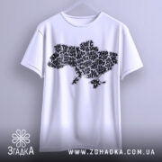 Футболка карта України білого кольору, підвішена на вішалці, з принтом у вигляді карти України, виконаним чорними літерами, на фоні світло-сірого кольору.