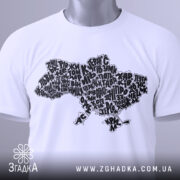 Футболка карта України білого кольору, складена на поверхні, з принтом у вигляді карти України, виконаним чорними літерами, з зеленим ярликом, на фоні світло-сірого кольору.
