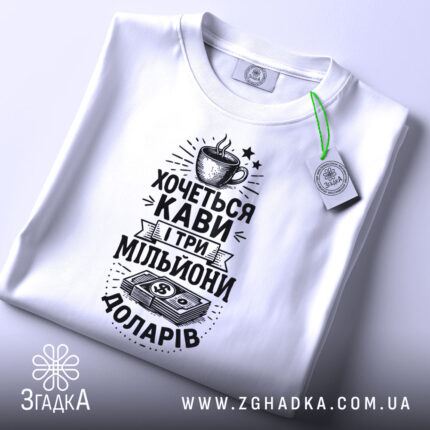 Футболка кава мільйони доларів, біла, складена на поверхні, фон світлий, принт чорного кольору з малюнком чашки кави та грошима, на комірці є етикетка.