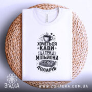 Футболка кава мільйони доларів, біла, складена на плетеній основі, фон світлий, принт чорного кольору з малюнком чашки кави та грошима.