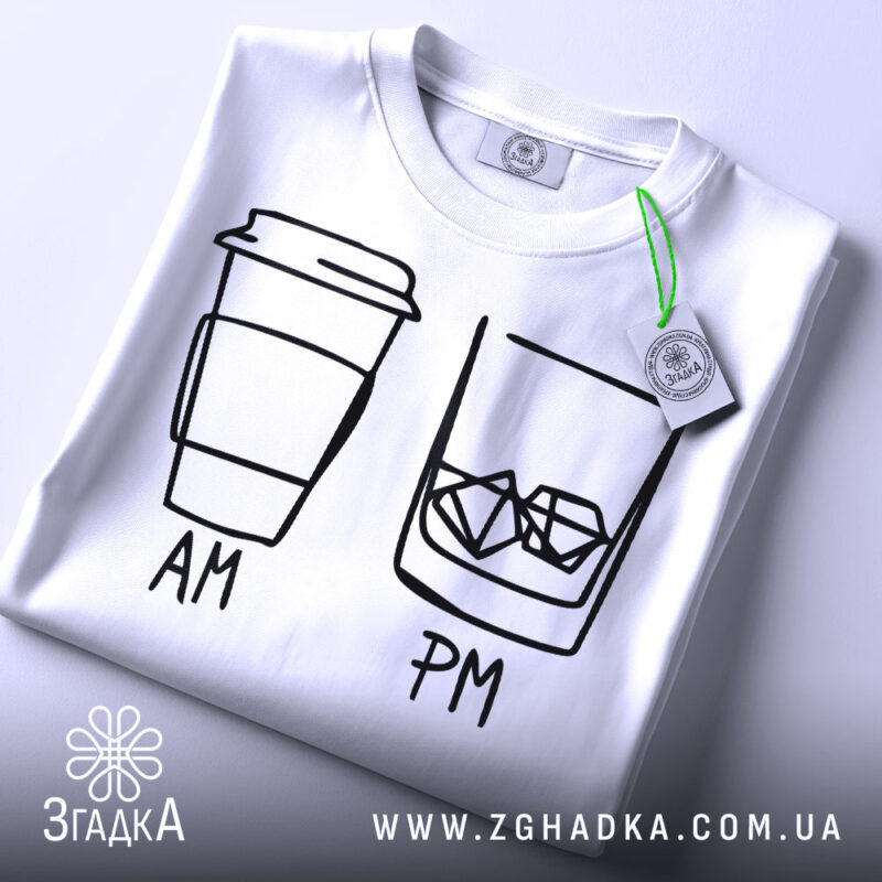 Футболка кава віскі, біла, складена на столі, фон світлий, принт з малюнком кави та склянки з льодом, підписами AM та PM, з етикеткою на рукаві.