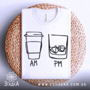 Футболка кава віскі, біла, складена на плетеній кошику, фон світлий, принт з малюнком кави та склянки з льодом, підписами AM та PM.