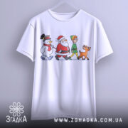 Футболка казковий настрій. Біла футболка, підвішена на вішалці, з принтом, що зображає Санту, сніговика, ельфа і оленя. Фон нейтральний, акцент на яскравих кольорах принта.
