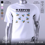 Футболка керую бджілочками, білого кольору, зображена на манекені з правого ракурсу, фон світло-сірий, принт з бджолами та написом "Я КЕРУЮ ЦИМИ БДЖІЛОЧКАМИ" в чорному кольорі.
