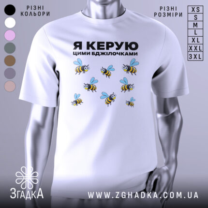 Футболка керую бджілочками, білого кольору, зображена на манекені з правого ракурсу, фон світло-сірий, принт з бджолами та написом "Я КЕРУЮ ЦИМИ БДЖІЛОЧКАМИ" в чорному кольорі.