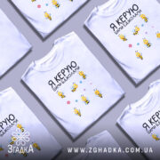 Футболка керую бджолами білого кольору, зображена на манекені, фон світло-сірий, принт з жовтими бджолами та квітами розташований по центру.