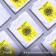 Футболка хаос мій план, біла, зображена на манекені, фон світло-сірий, принт з жовтим фоном і чорним малюнком, що зображає людину з заплутаним волоссям.