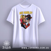 Футболка Харлі Квін білого кольору, підвішена на вішалці, фон світло-сірий. Принт зображає Харлі Квін з двома різними стилями, з написом 'HIS HARLEY' у верхній частині.