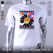 Футболка хейт квітка стиль, біла футболка на манекені, з принтом у вигляді квітки з усміхненим обличчям, кольори принта яскраві: червоний, жовтий, синій, чорний, фон світло-сірий.