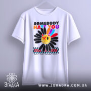 Футболка хейт квітка стиль, біла футболка на вішалці, з принтом квітки та текстом, фон світло-сірий, футболка має вільний крій.