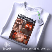 Футболка Херобрін майнкрафт білого кольору, складена на поверхні, фон світлий, принт аналогічний попередньому, з додатковим зеленим ярликом.