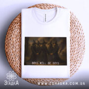 Футболка хлопці магія, біла, складена на кошику, фон світлий, принт з чотирма чоловіками в чорних мантіях та капелюхах, текст 'BOYS WILL BE BOYS' під малюнком.