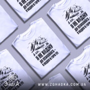 Футболка ходжу в гори, білого кольору, зображена на манекені з правого боку, фон світло-сірий, принт з горами та текстом чорного кольору.