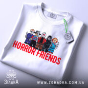 Футболка хорор друзі, біла, складена на столі, фон світло-сірий, принт з персонажами в стилі LEGO, текст 'HORROR FRIENDS' червоним кольором, на футболці є етикетка.