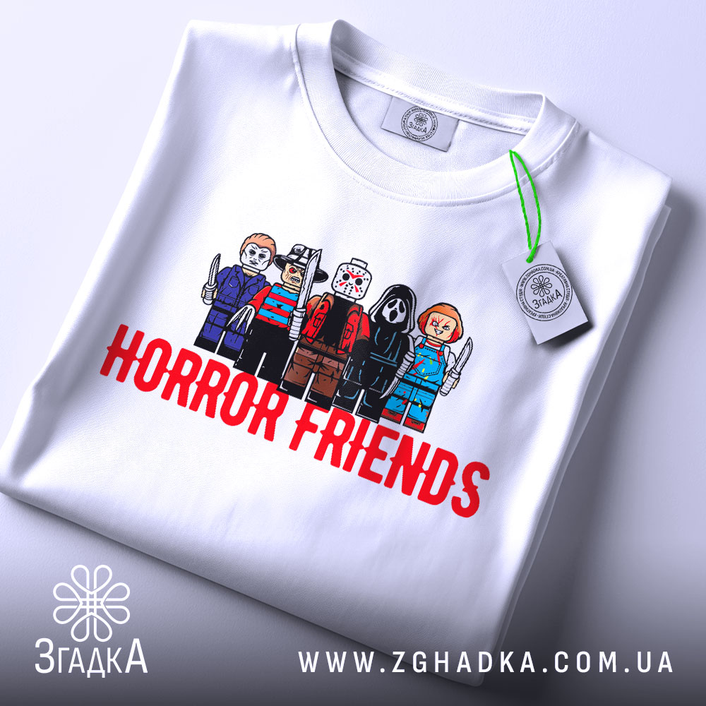 Футболка хорор друзі, біла, складена на столі, фон світло-сірий, принт з персонажами в стилі LEGO, текст 'HORROR FRIENDS' червоним кольором, на футболці є етикетка.