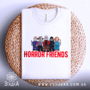 Футболка хорор друзі, біла, складена на плетеній кошику, фон світло-сірий, принт з персонажами в стилі LEGO, текст 'HORROR FRIENDS' червоним кольором.
