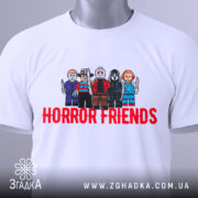 Футболка хорор друзі, біла, складена на столі, фон світло-сірий, принт з персонажами в стилі LEGO, текст 'HORROR FRIENDS' червоним кольором, на футболці є етикетка.