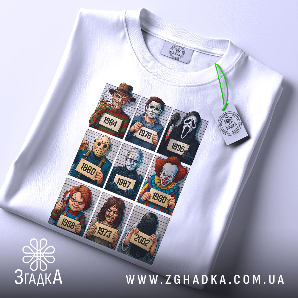 Футболка хорор класика, біла, зображена зверху, фон світло-сірий, принт містить дев'ять персонажів з фільмів жахів, на футболці є етикетка з зеленим шнурком, деталі принта яскраві і чіткі.
