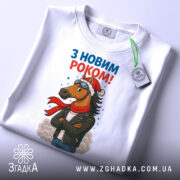 Футболка кінь з новим роком, біла, складена на поверхні, фон світло-сірий, принт з кінем у шапці та шарфі, напис 'З НОВИМ РОКОМ!' у верхній частині, на футболці є етикетка.
