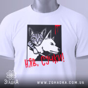 Футболка кіт бунтар, біла, складена на поверхні, фон світло-сірий, принт з котом і собакою в чорному квадраті, червоний напис 'НЯВ, СУЧКИ!' з краплинами червоного, на комірці є етикетка.