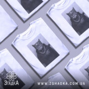 Футболка кіт гангстер стиль, біла футболка з принтом кота в гангстерському стилі, ракурс спереду, фон світло-сірий, принт зображує кота в капелюсі та з пістолетом, на шиї ланцюг.