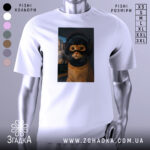 Футболка кіт геймер, біла, зображена з фронтального ракурсу, на фоні світло-сірого градієнту, принт з котом у навушниках та масці геймера, з виразними очима та деталями шерсті.