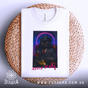 Футболка кіт якось живу, біла, зображена з верхнього ракурсу, на фоні плетеного кошика, принт з котом у чорному костюмі, що тримає келих червоного вина та монети, з неоновим колом навколо голови кота.